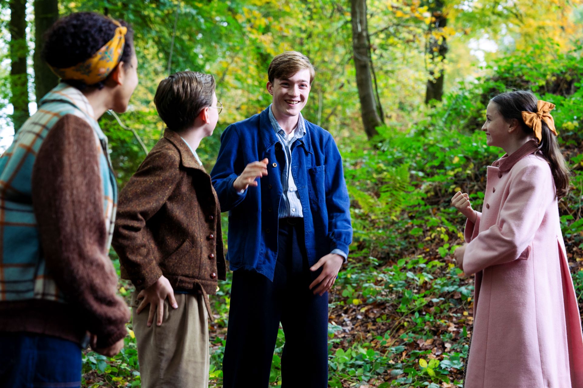 Four children stand together laughing