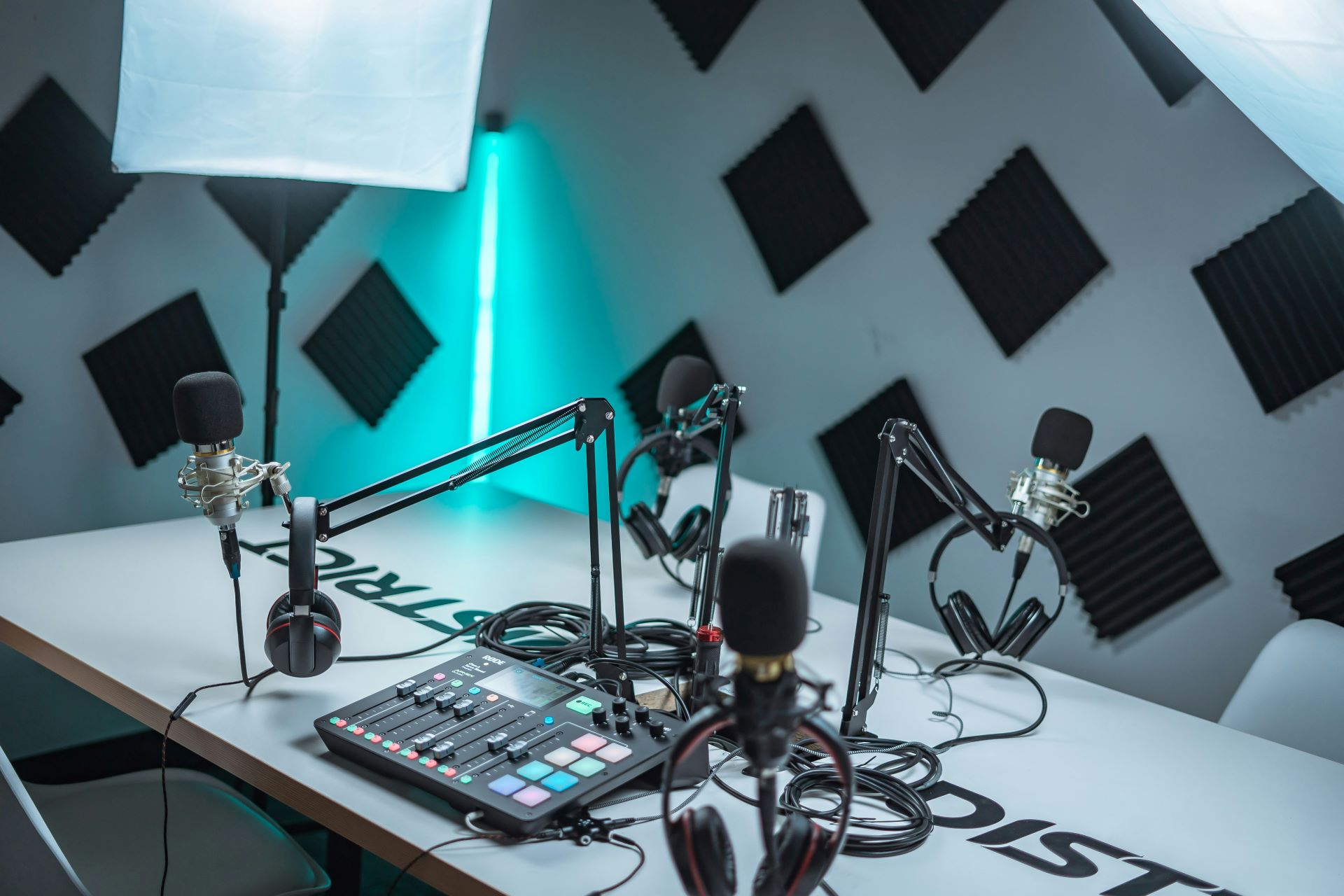 A studio space set up with microphones and headphones around a table with a sound mixer in the centre.