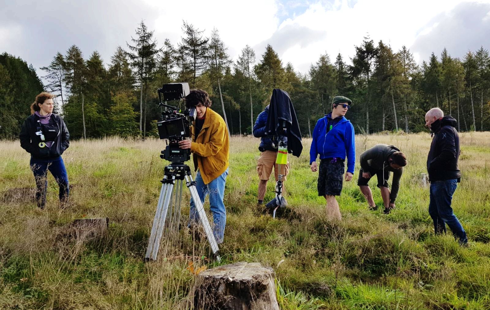 Camera crew standing in a grassy area 