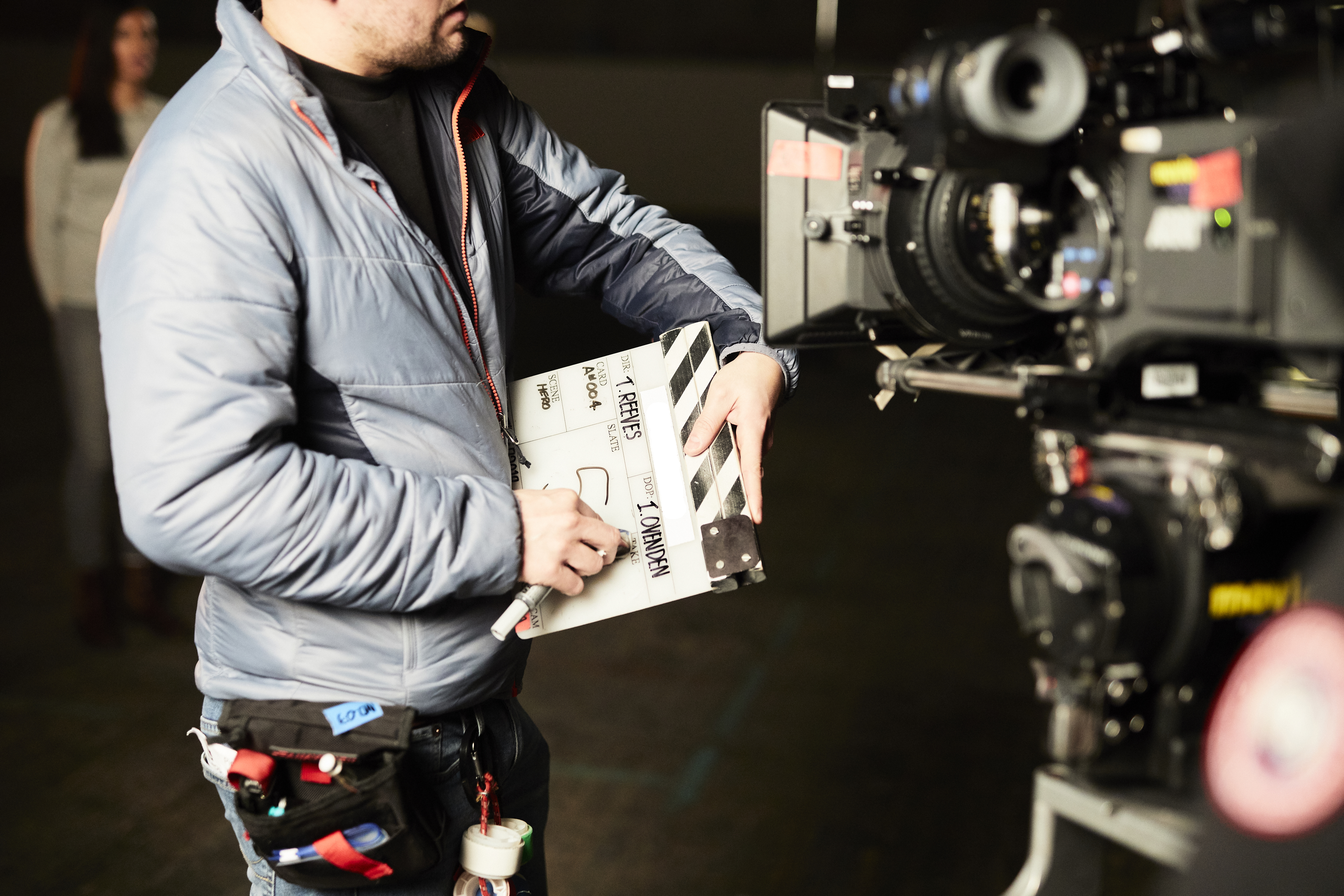 Person stands in front of a camera with a clapperboard