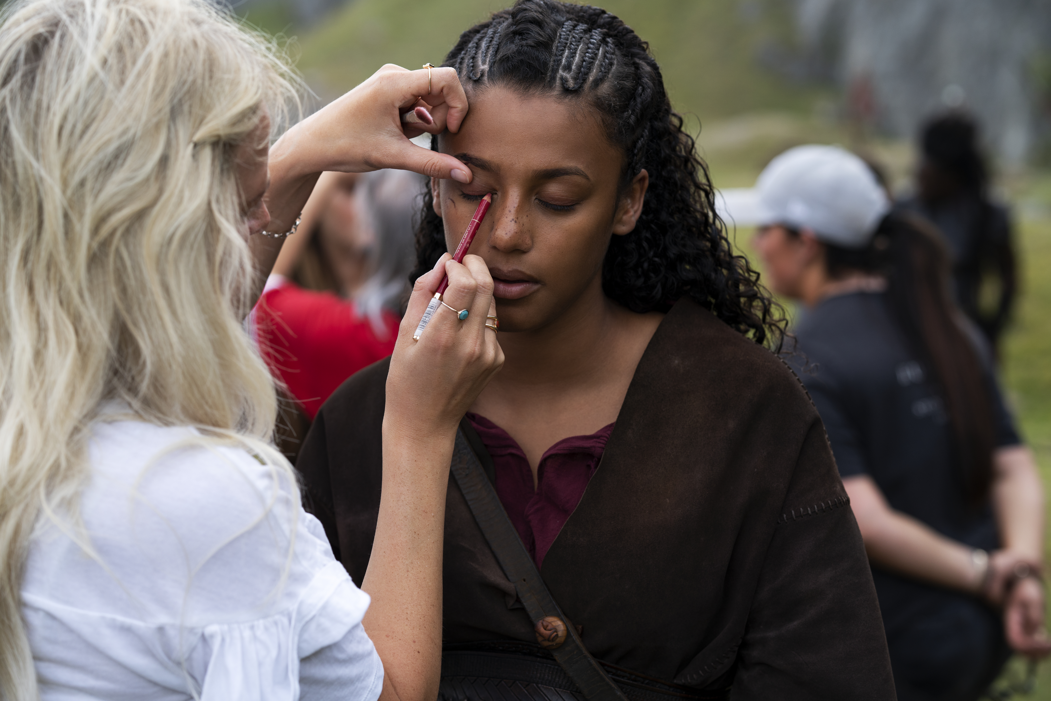 Woman applies eyeliner to female actress on location