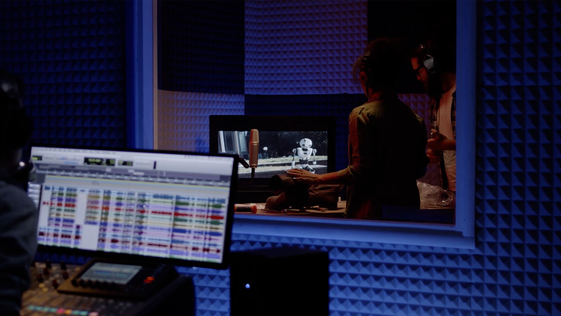 Two voice actors standing together recording in an audio booth