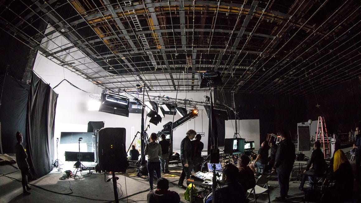 Wide shot of a set with lights, camera, crew and monitors