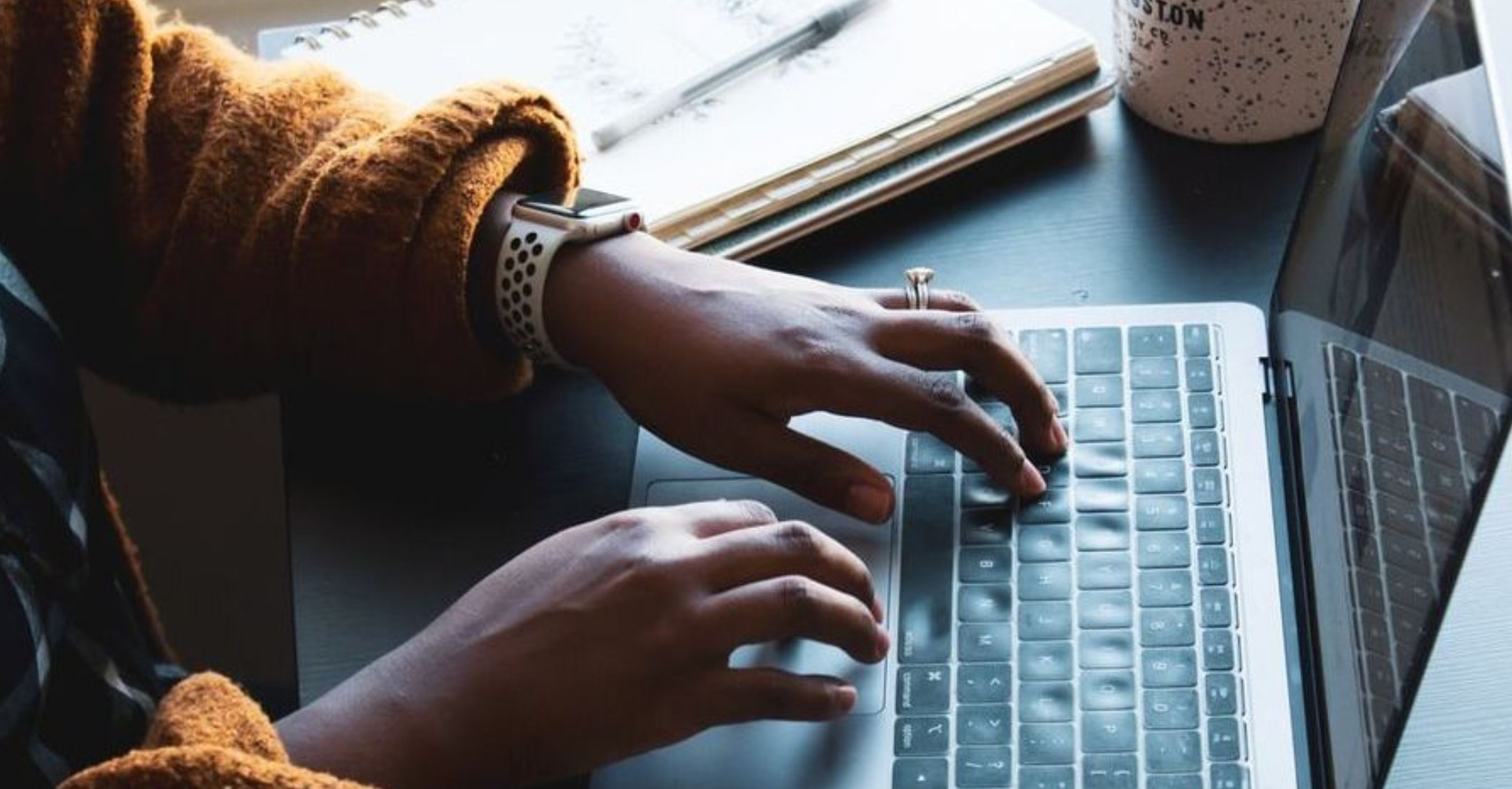 Close up of hands tapping on a laptop keyboard on a desk