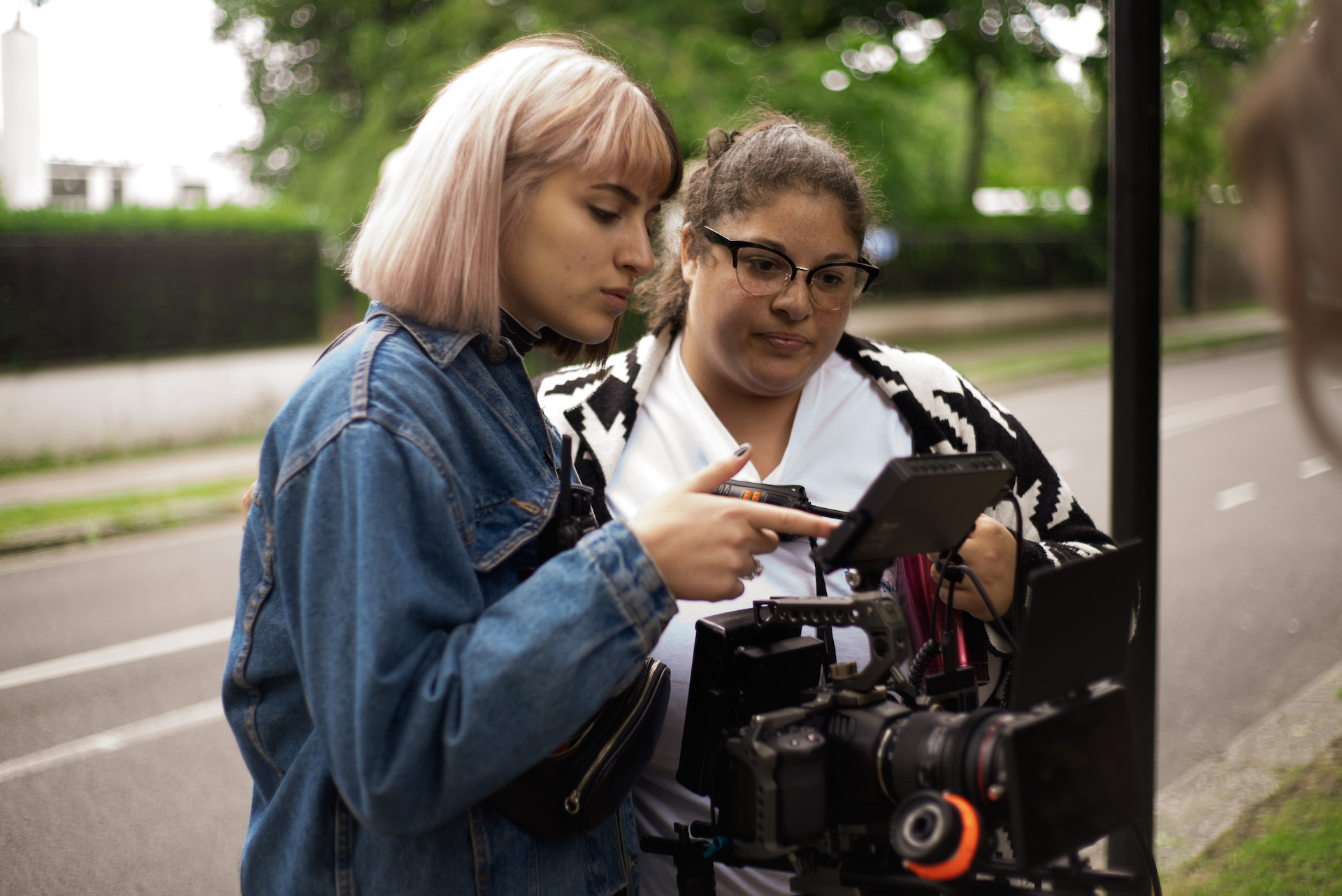 Two young women look at view finder on a television camera on location on a street