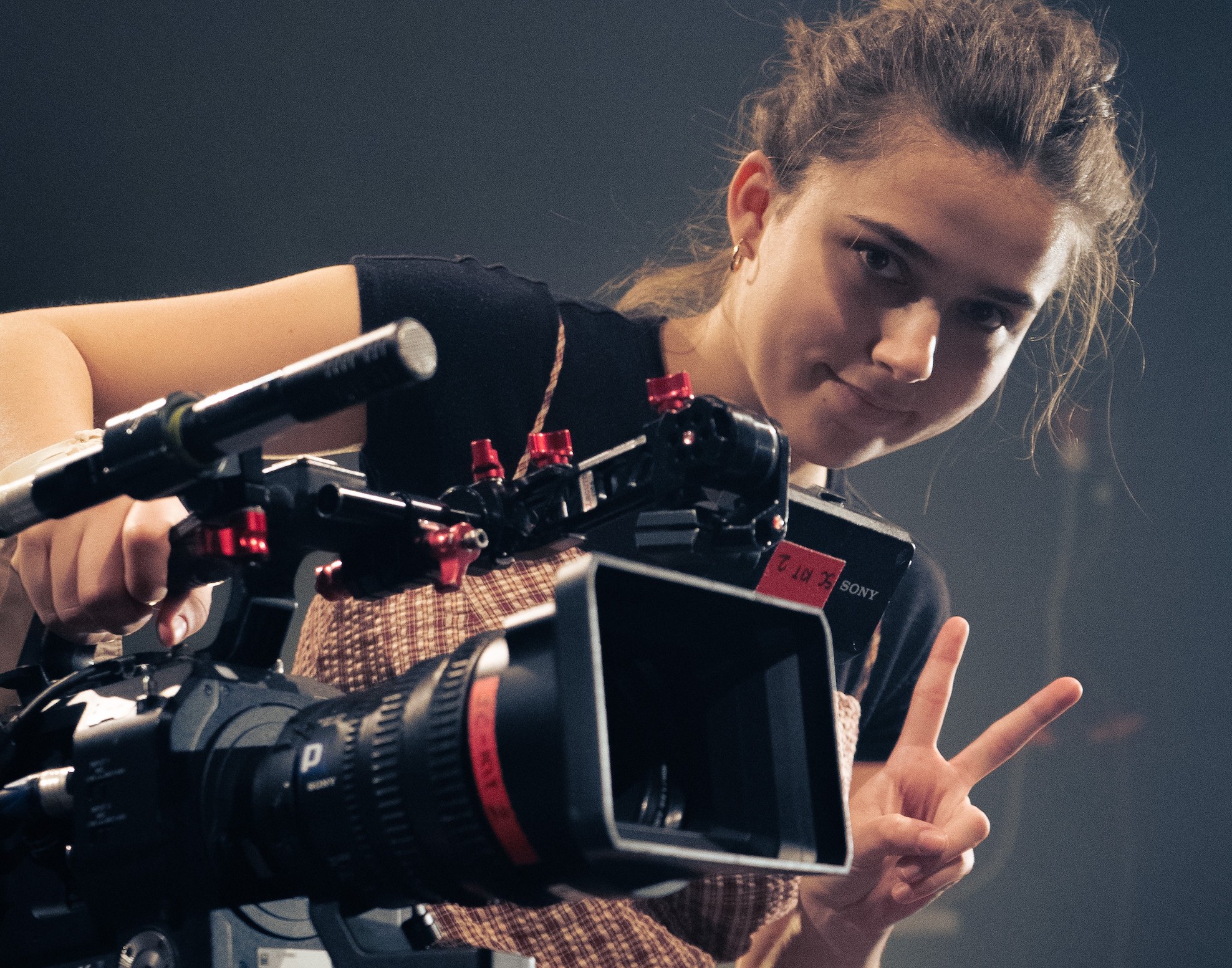 Young woman holding a camera gives a 'V' sign