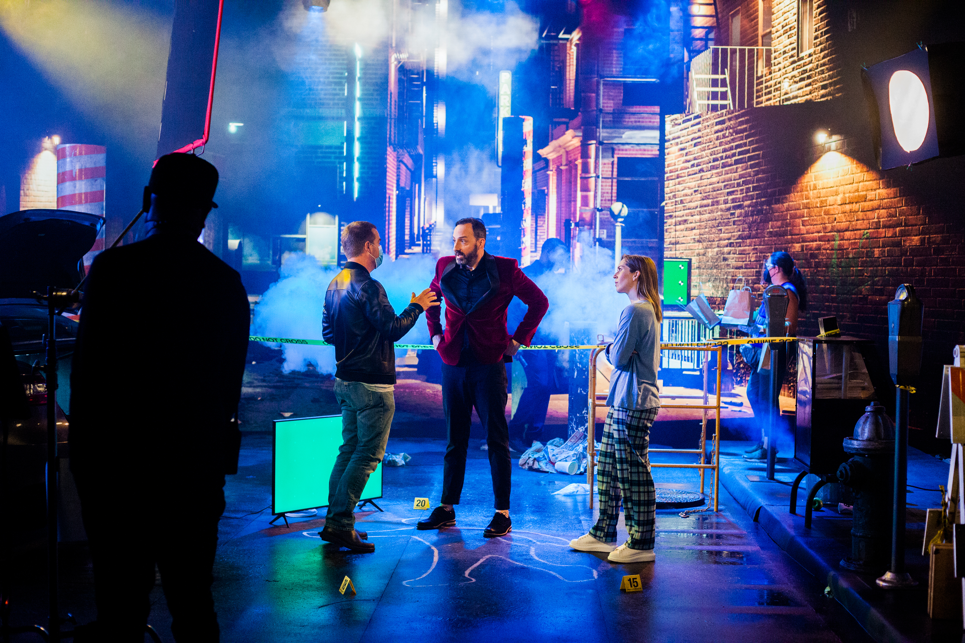 Crew in front of a screen showing the back of an alley