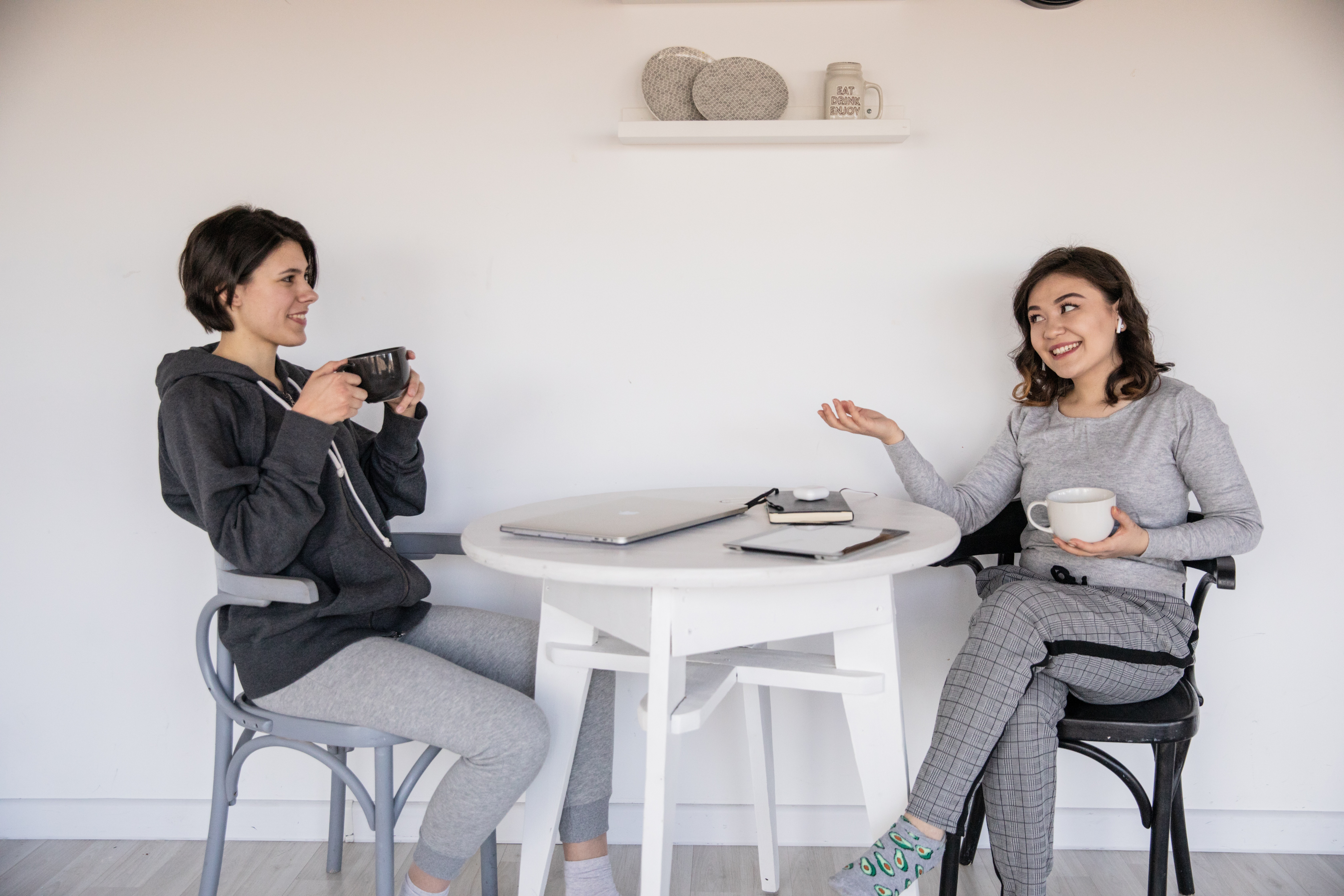 Two women sat at a table drinking coffee and chatting