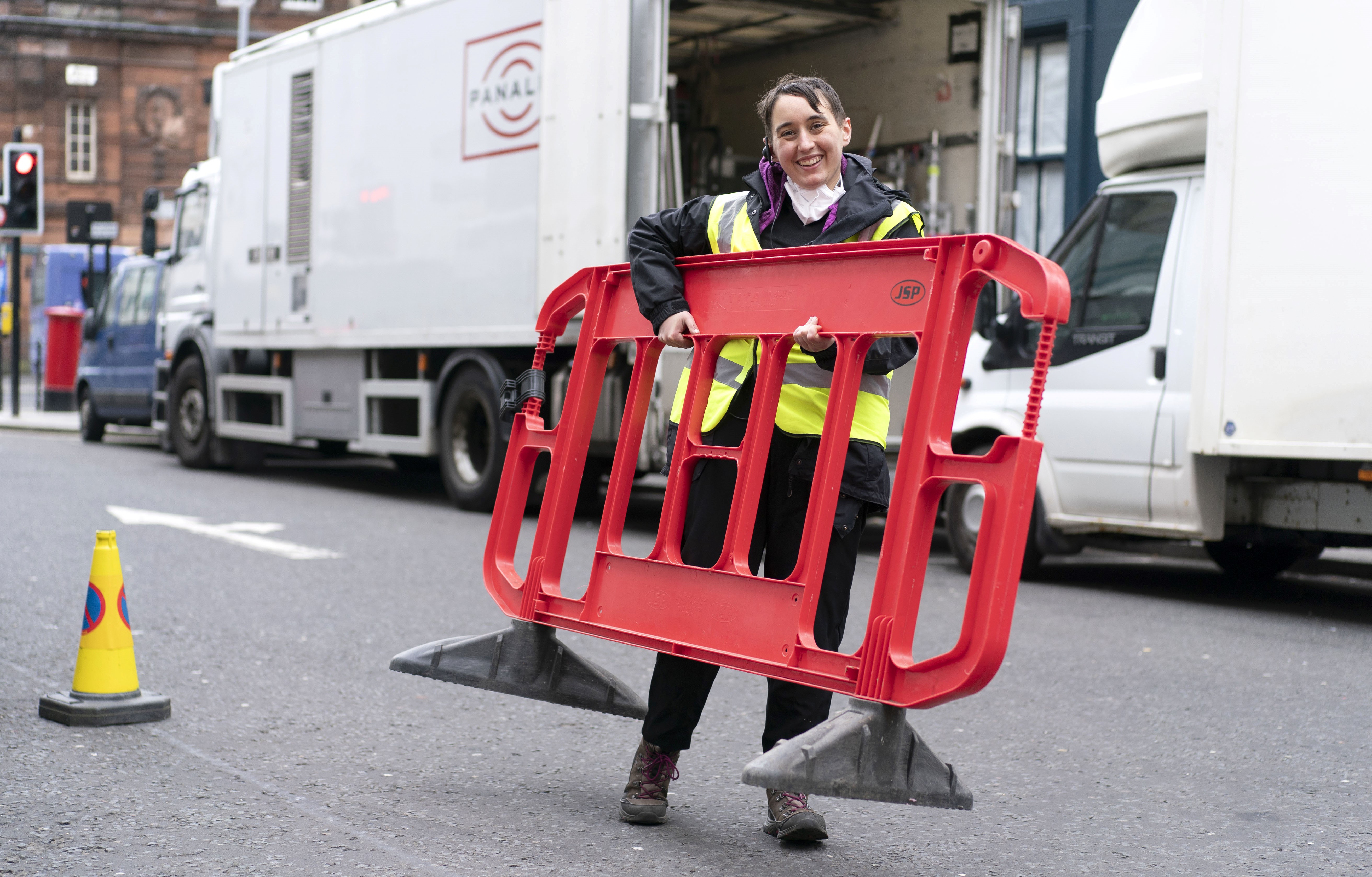 Assistant in high-visibility vest lifting portable fence