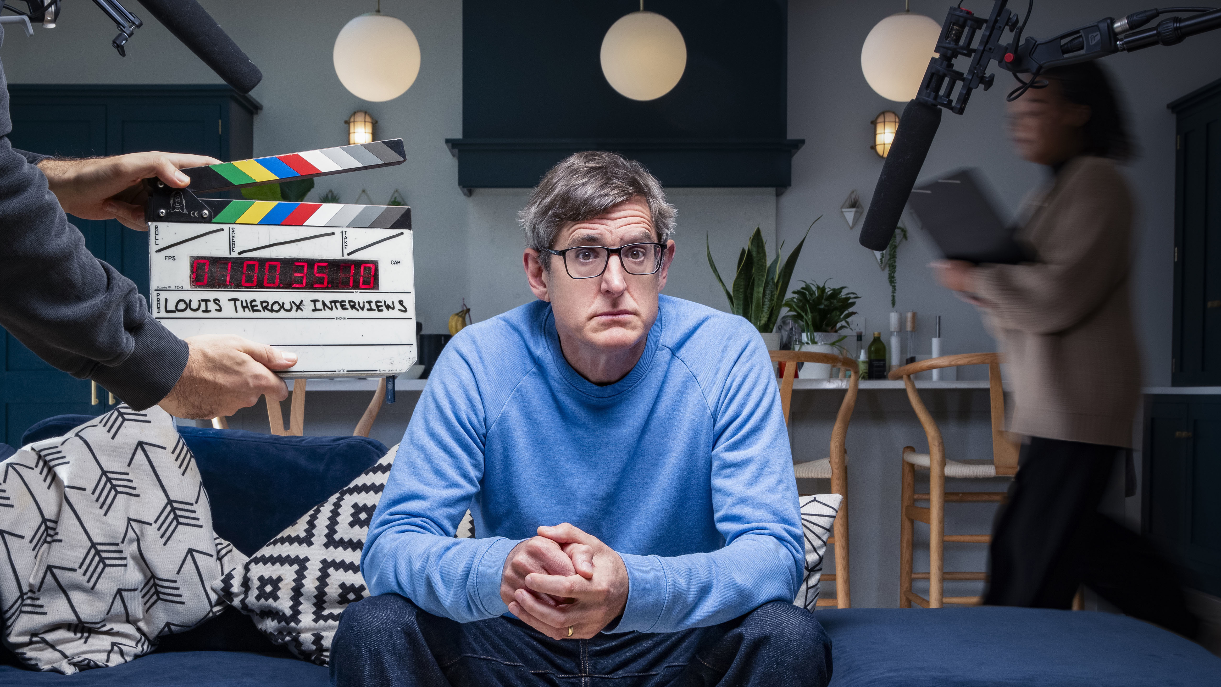 Louis Theroux sitting on a sofa in front of a clapper board