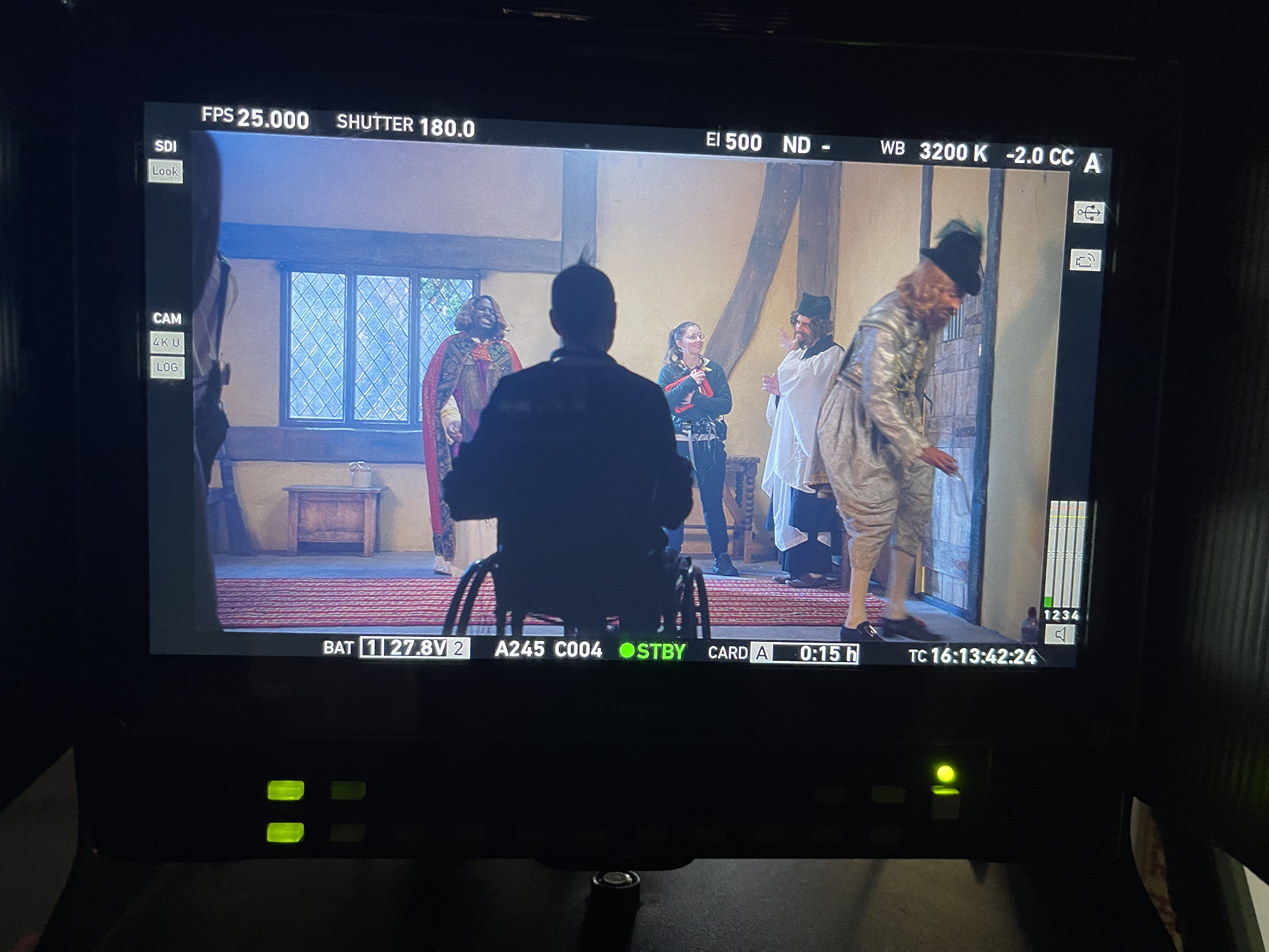 A screen showing a group of actors dressed in medieval clothes shooting a scene