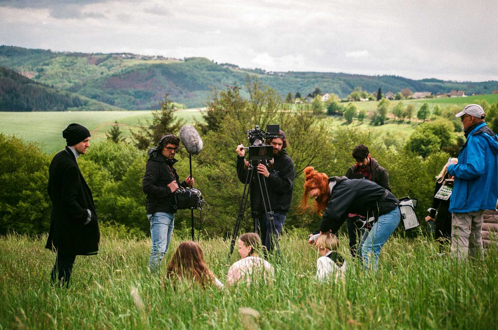 A film crew shoot a scene in a grassy hill landscape