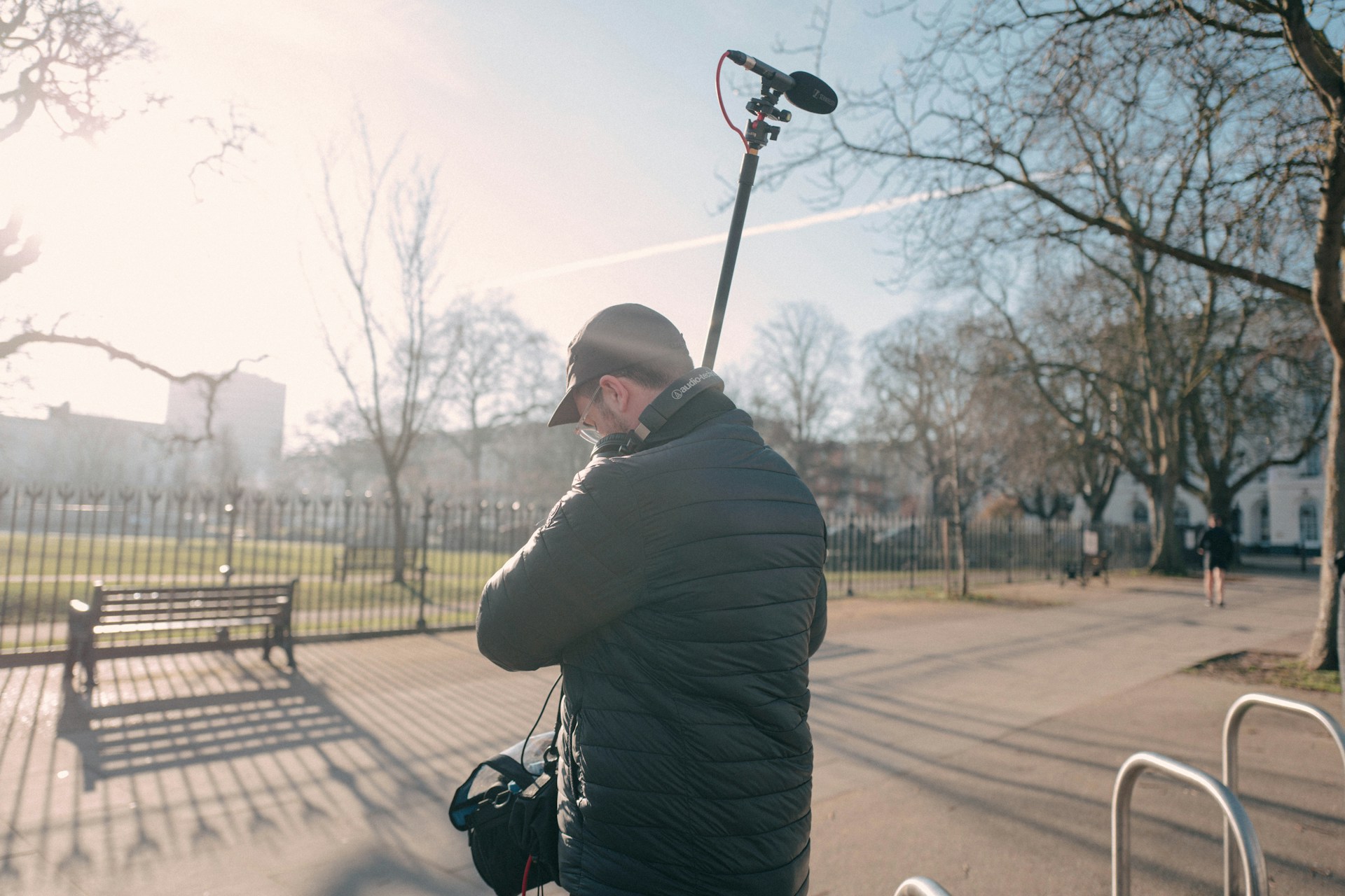 A sound recordists holds a microphone attached to a long extension pole