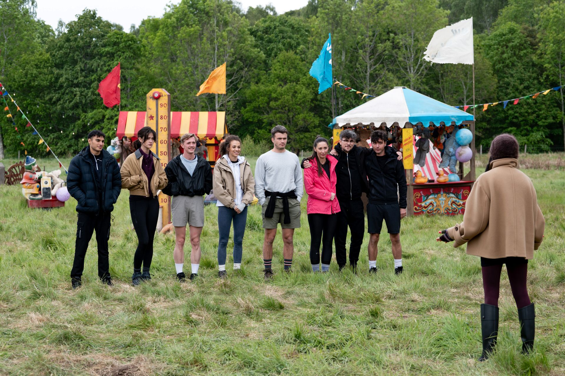 The cast of The Traitors S4 and Claudia Winkleman stand outside in a fairground set
