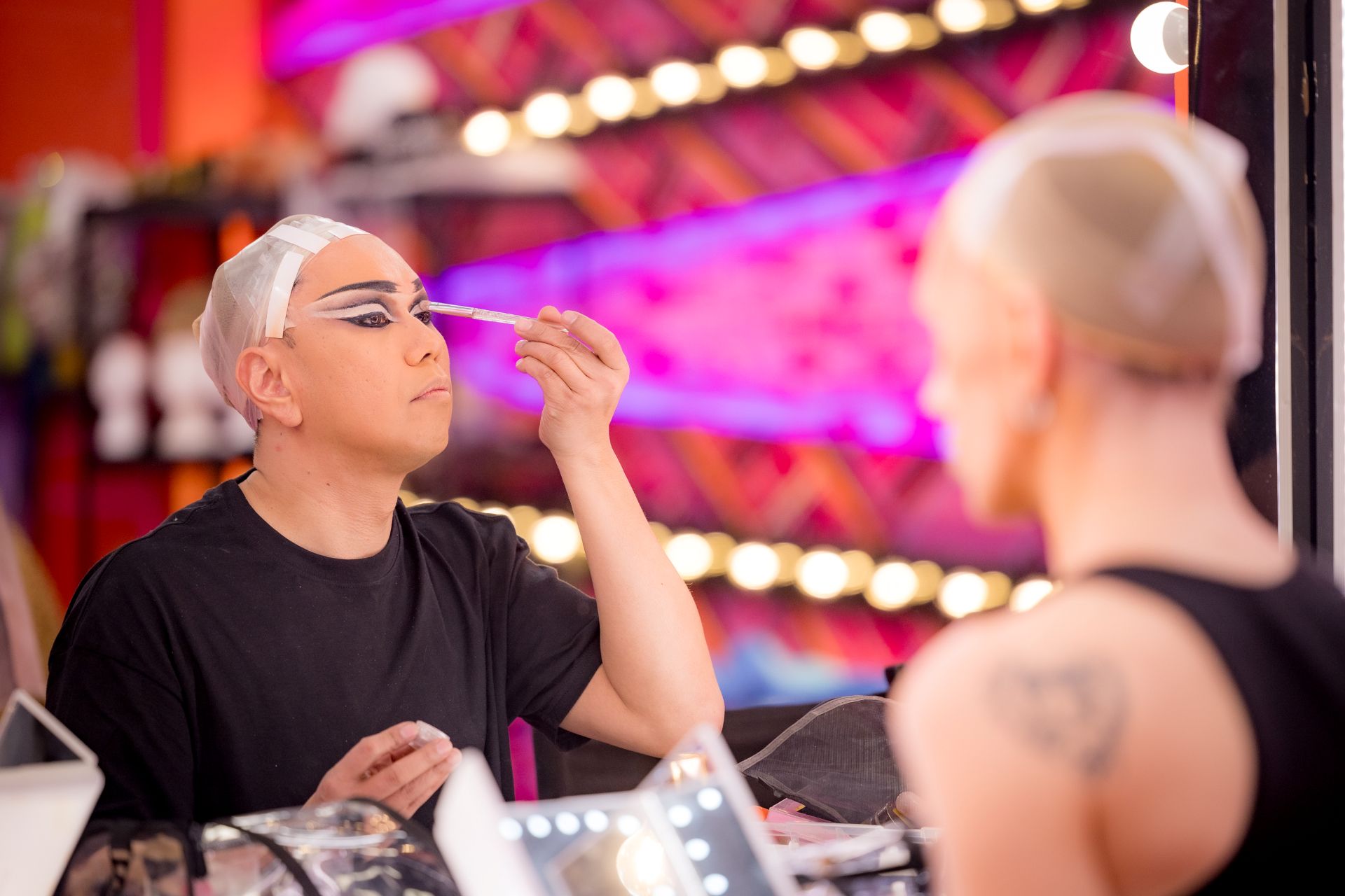 A person sits applying their make-up in a mirror