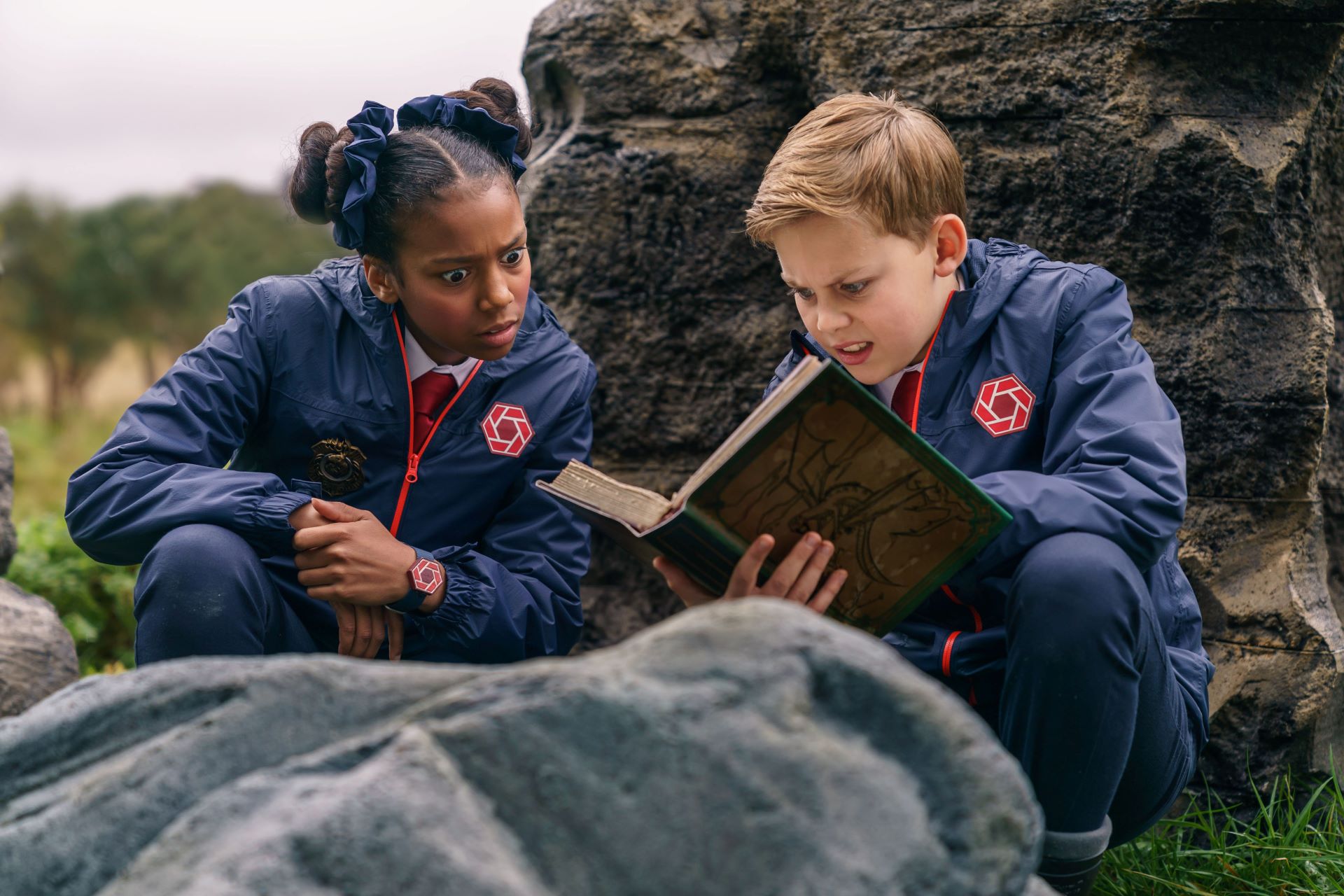 Two children look at a book, visibly perplexed