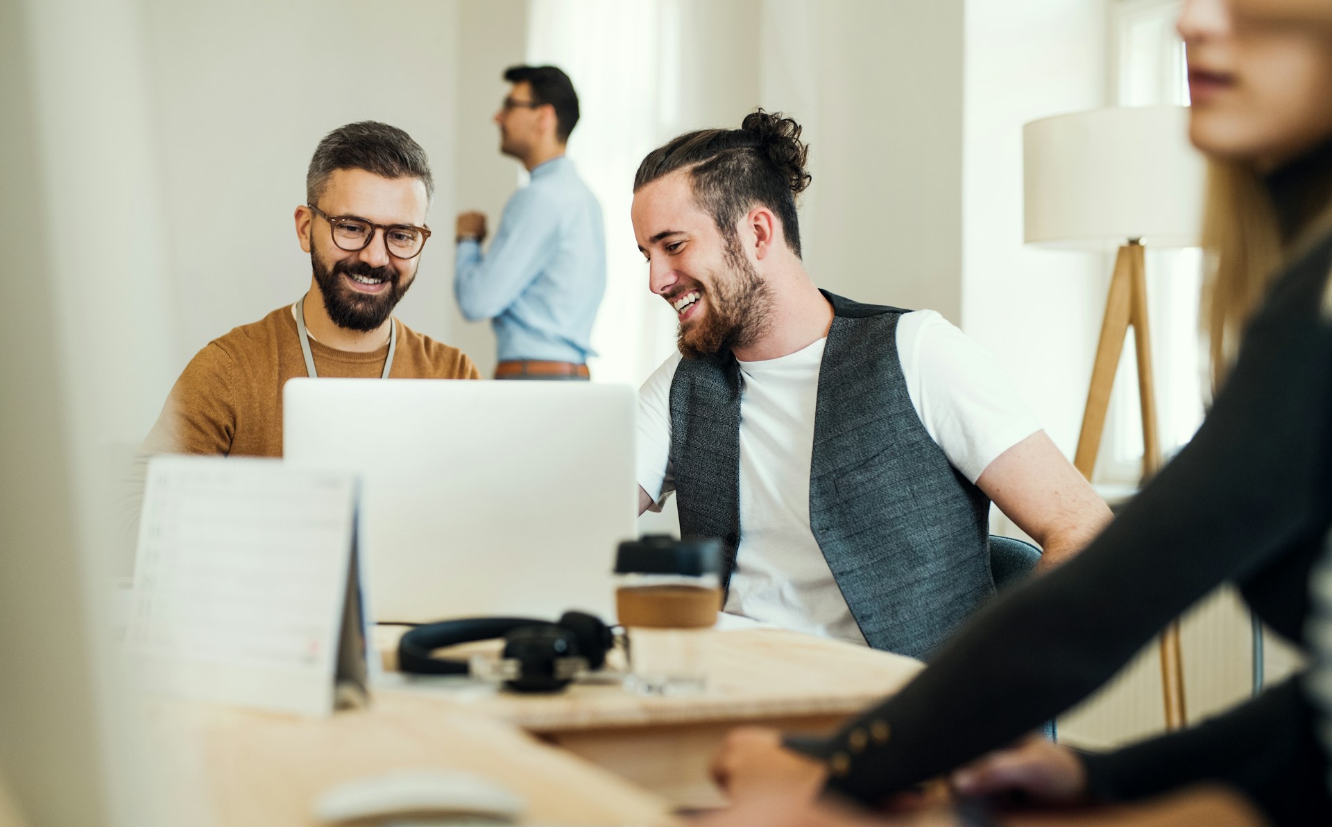 Two men look at a laptop screen in an office
